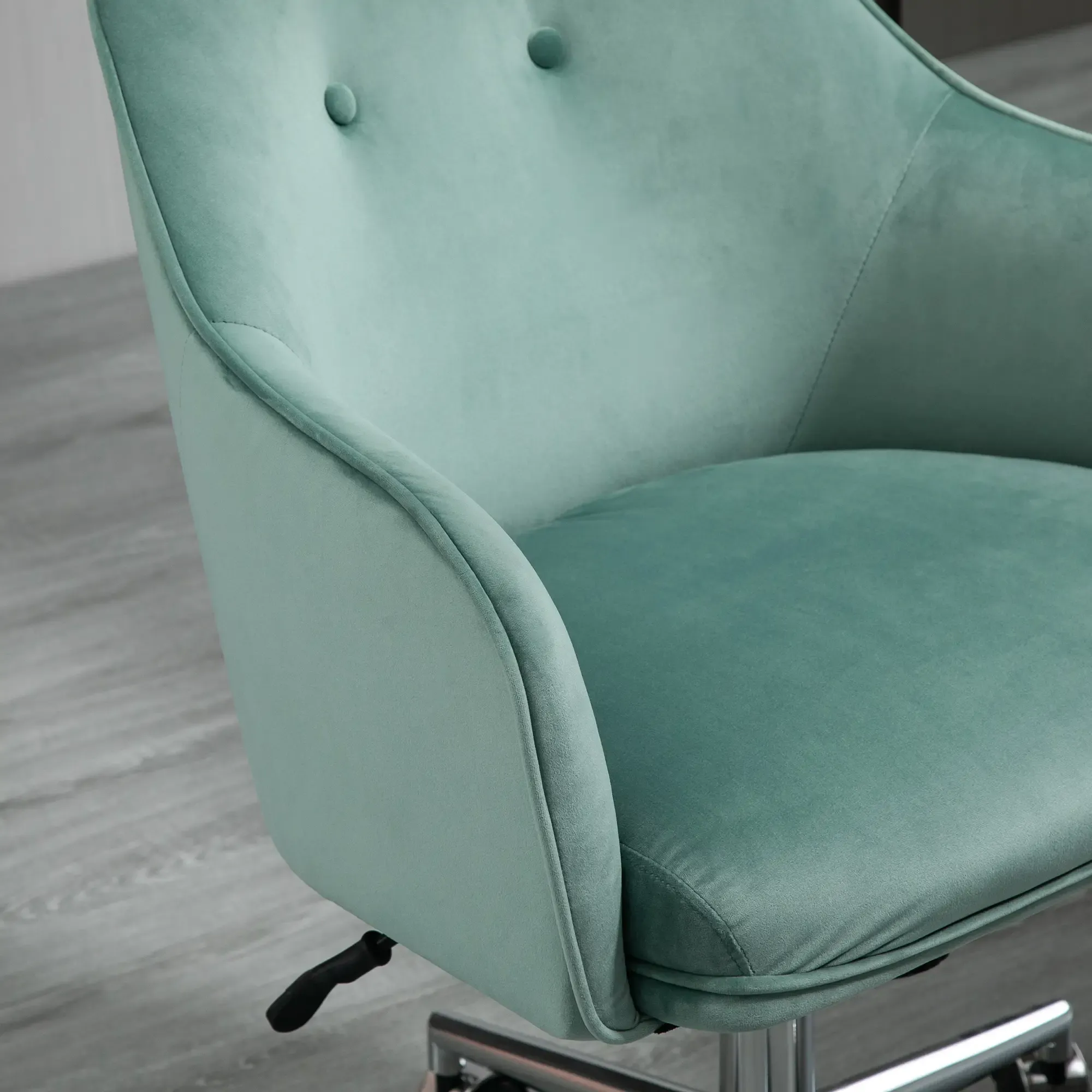 Ein teal-farbener Samt-Bürostuhl. Der Stuhl hat einen gepolsterten Sitz, Rückenlehne und Armlehnen. Er steht auf einem silbernen Sockel mit Rädern.