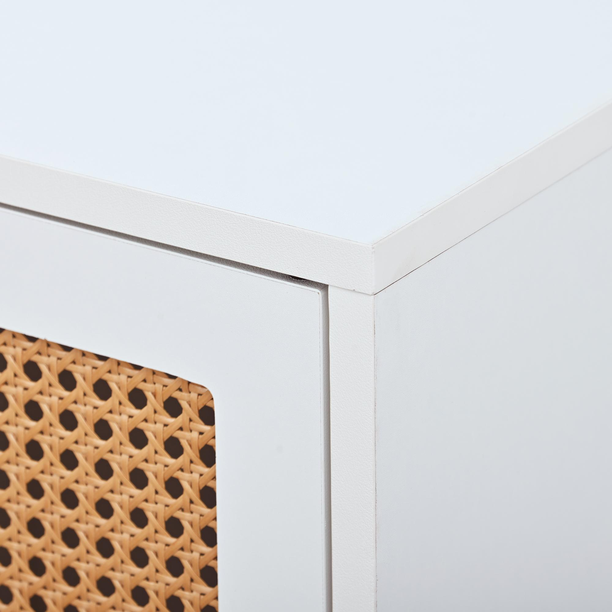 Nahaufnahme einer weißen Schrankecke mit einer Türverkleidung aus gewebtem Rattan. Helle Beleuchtung.