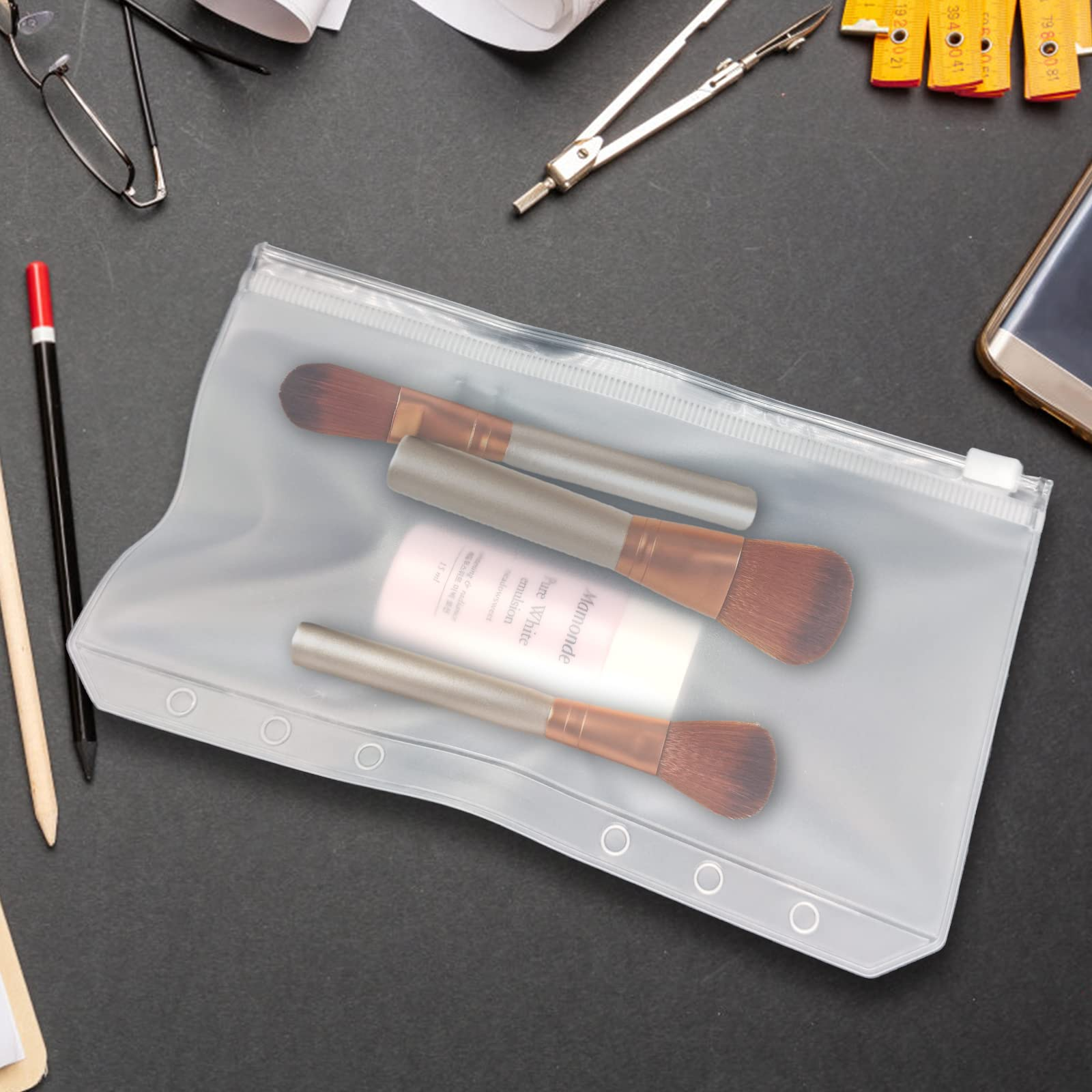Transparente Tasche mit Make-up-Pinseln und Hautpflegeprodukten auf dunkler Oberfläche, Schreibwaren.