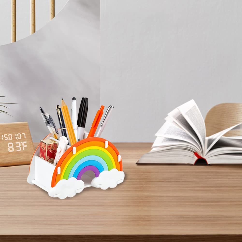 Ein Schreibtisch mit einem Regenbogen-Stifthalter, Stiften und einem offenen Buch. Eine kleine Holzuhr befindet sich links.