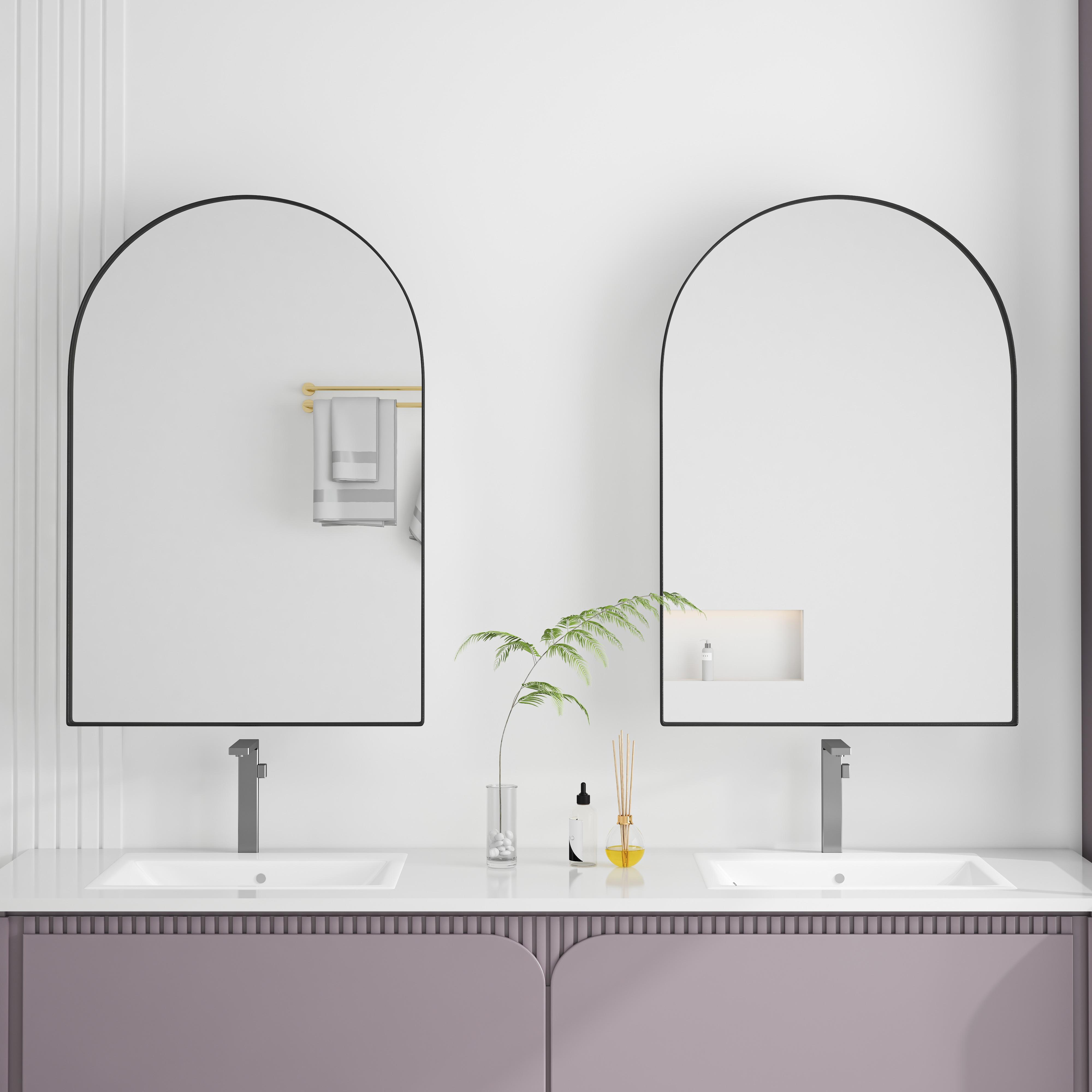 Ein modernes Badezimmer mit zwei gewölbten Spiegeln über Waschbecken. Auf der Arbeitsplatte stehen Pflanzen und Toilettenartikel.