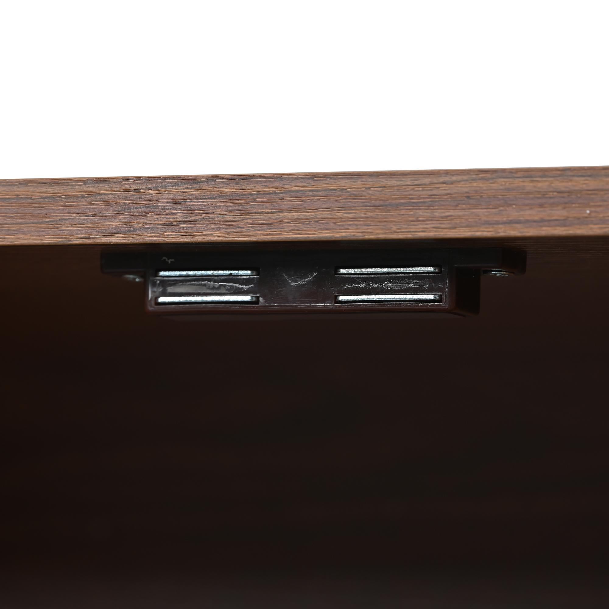 Nahaufnahme eines Holzschranks. Ein dunkelbrauner Magnetverschluss ist an der Unterseite des oberen Paneels befestigt.