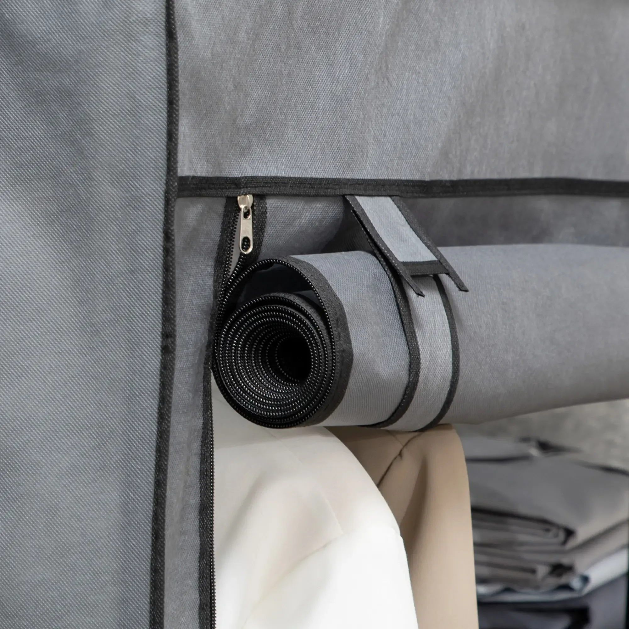 Eine gerollte graue Kleiderschutzhülle ist geöffnet und zeigt weiße und beige Kleidung. Die Tasche ist grau, mit einem schwarzen Reißverschluss.