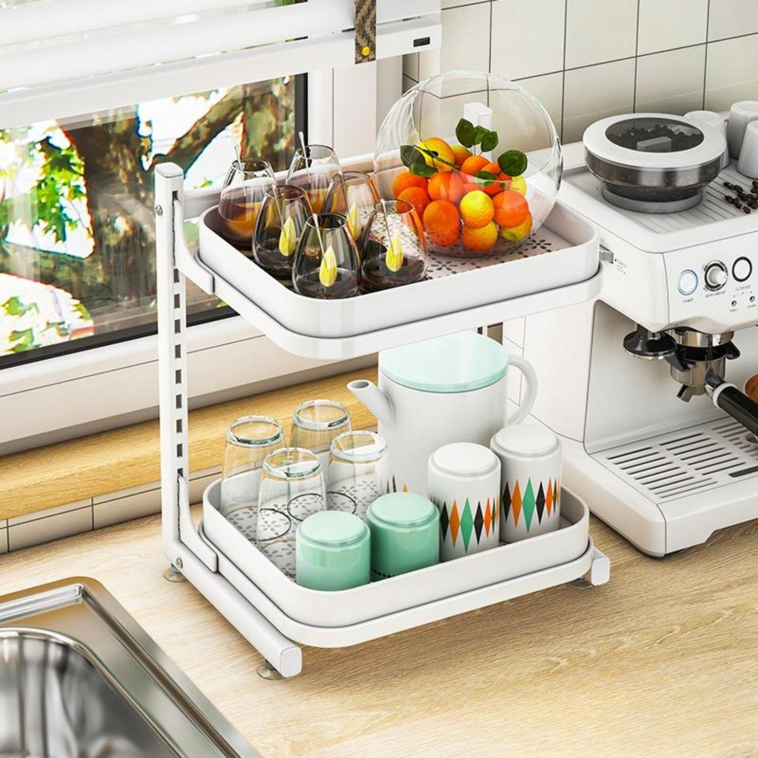Ein zweistöckiges weißes Regal mit Gläsern, einer Teekanne und einer Obstschale. Im Hintergrund eine Kaffeemaschine. Ein Fenster ist oben.