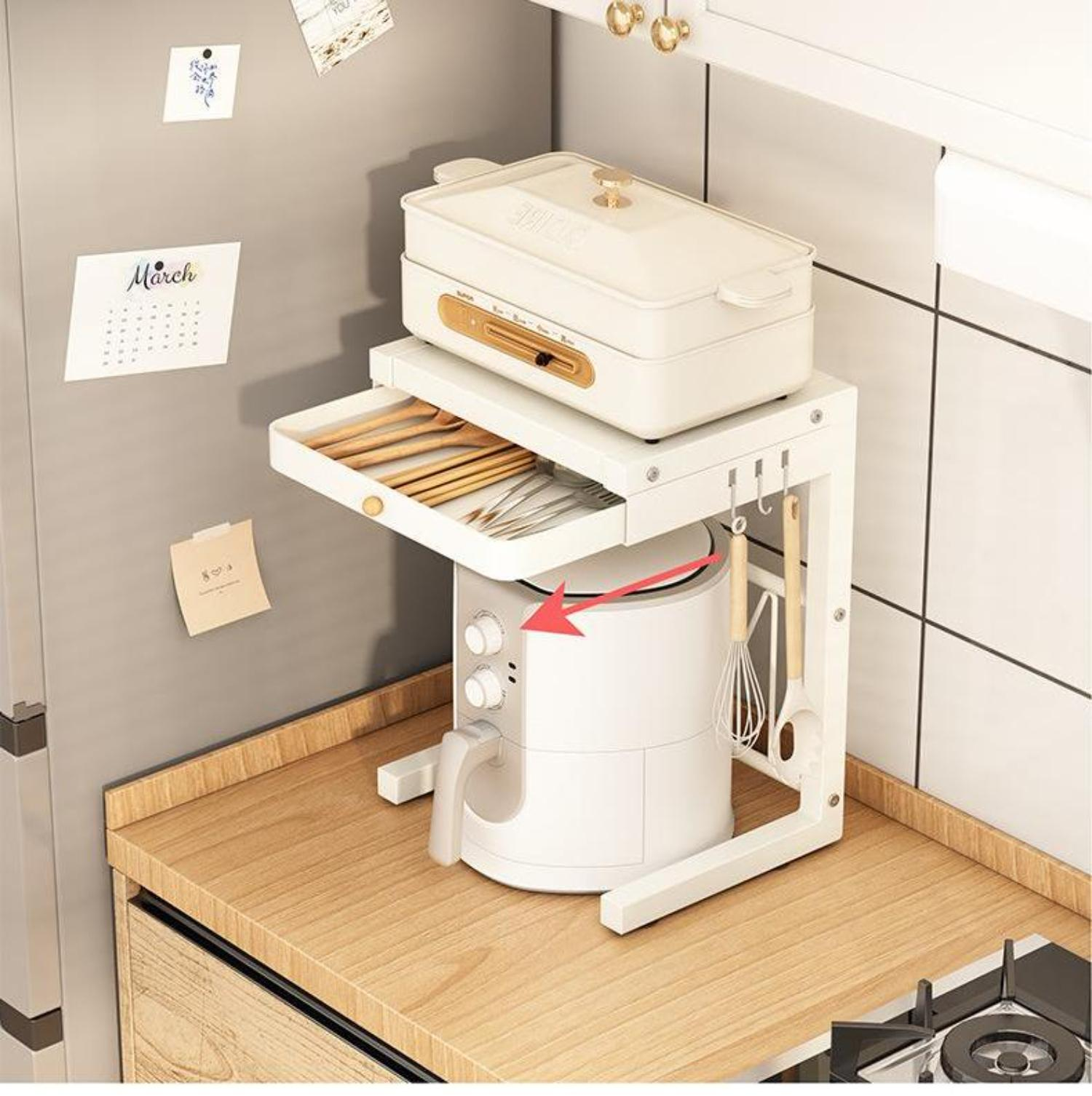 Ein weißer Küchenorganisator mit einer Heißluftfritteuse, einer Schublade mit Utensilien und einem Dampfgarer. Ein Kalender und Notizen befinden sich auf dem Kühlschrank.