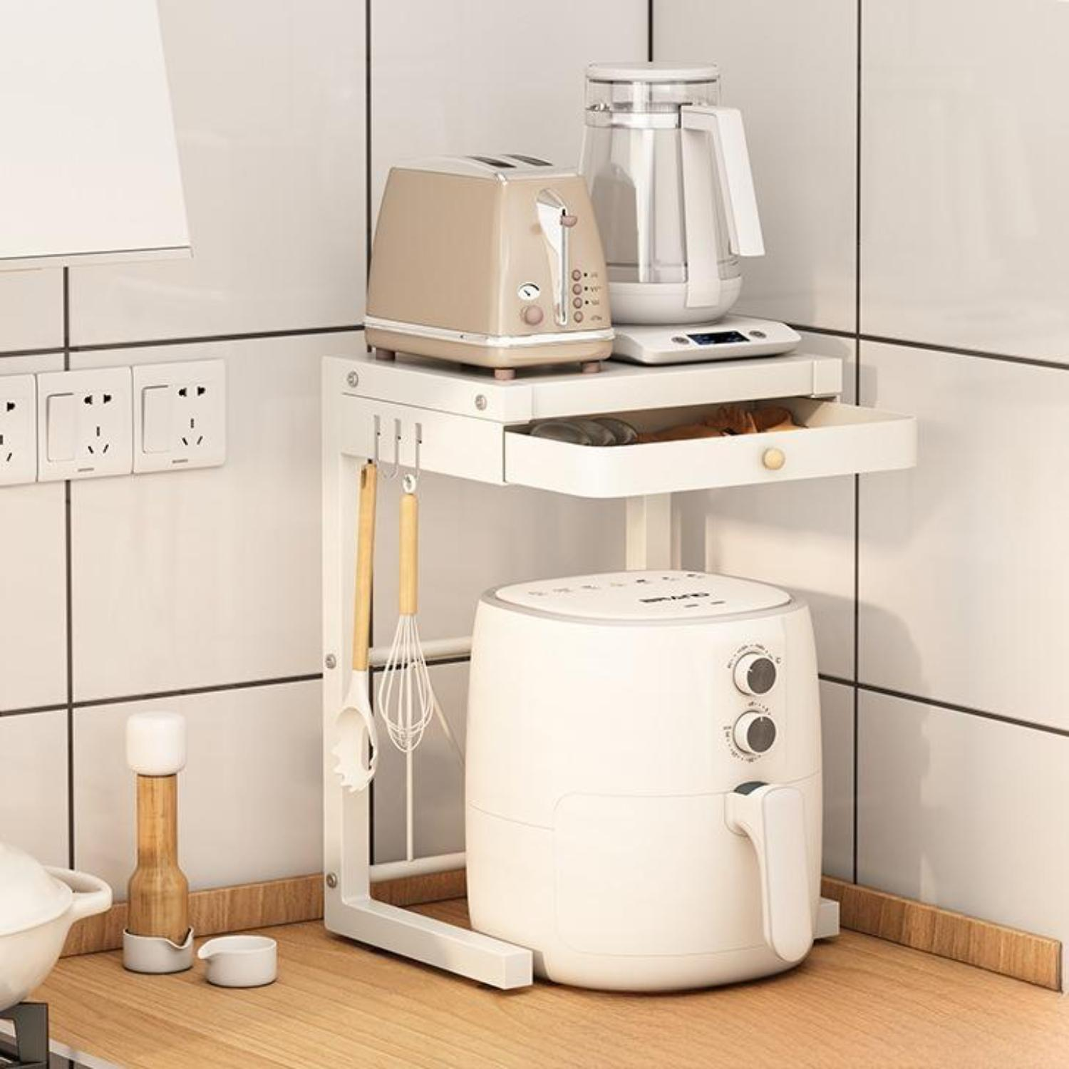 Eine Küchenzeile mit einem weißen Regal, das einen Toaster, einen Wasserkocher und eine Heißluftfritteuse enthält. Darunter hängen Utensilien.