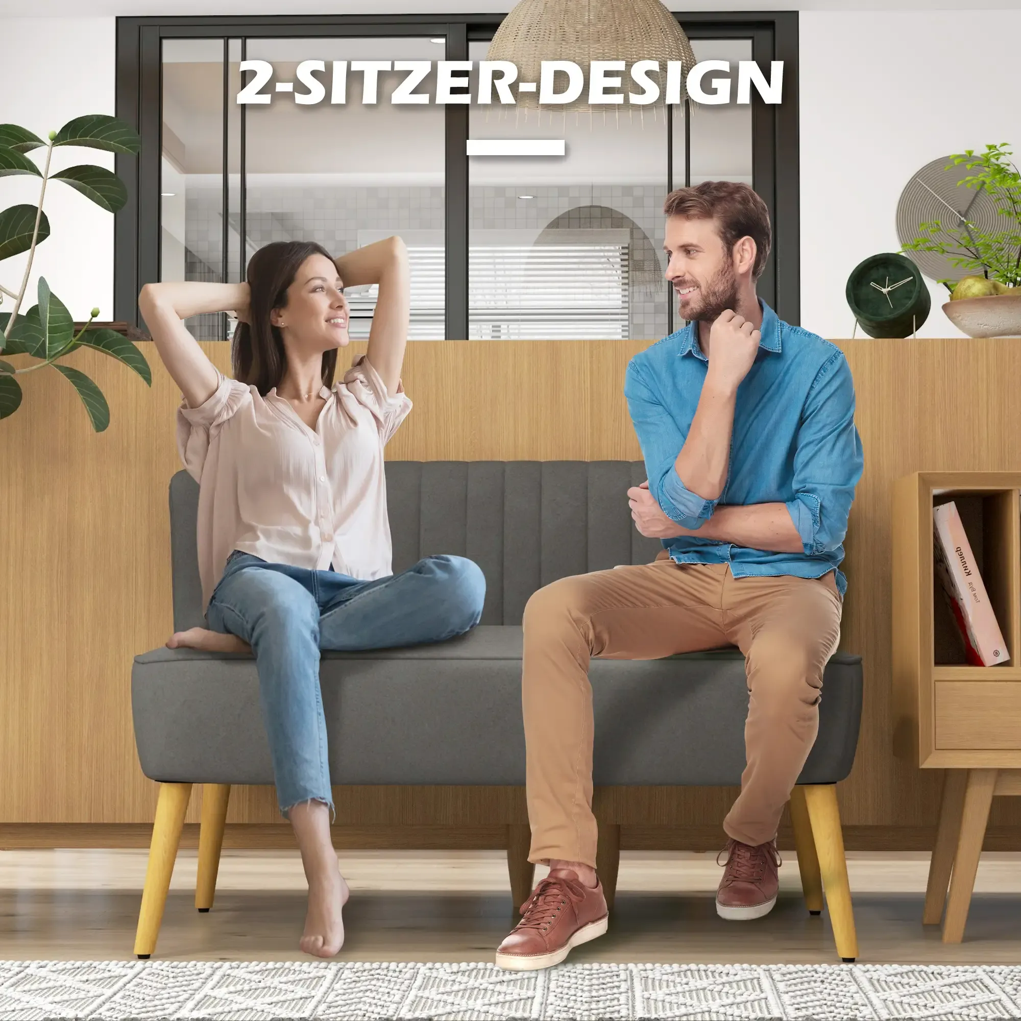Ein Mann und eine Frau sitzen auf einem grauen Sofa. Die Frau hat die Arme hinter dem Kopf. Der Mann berührt sein Kinn.
