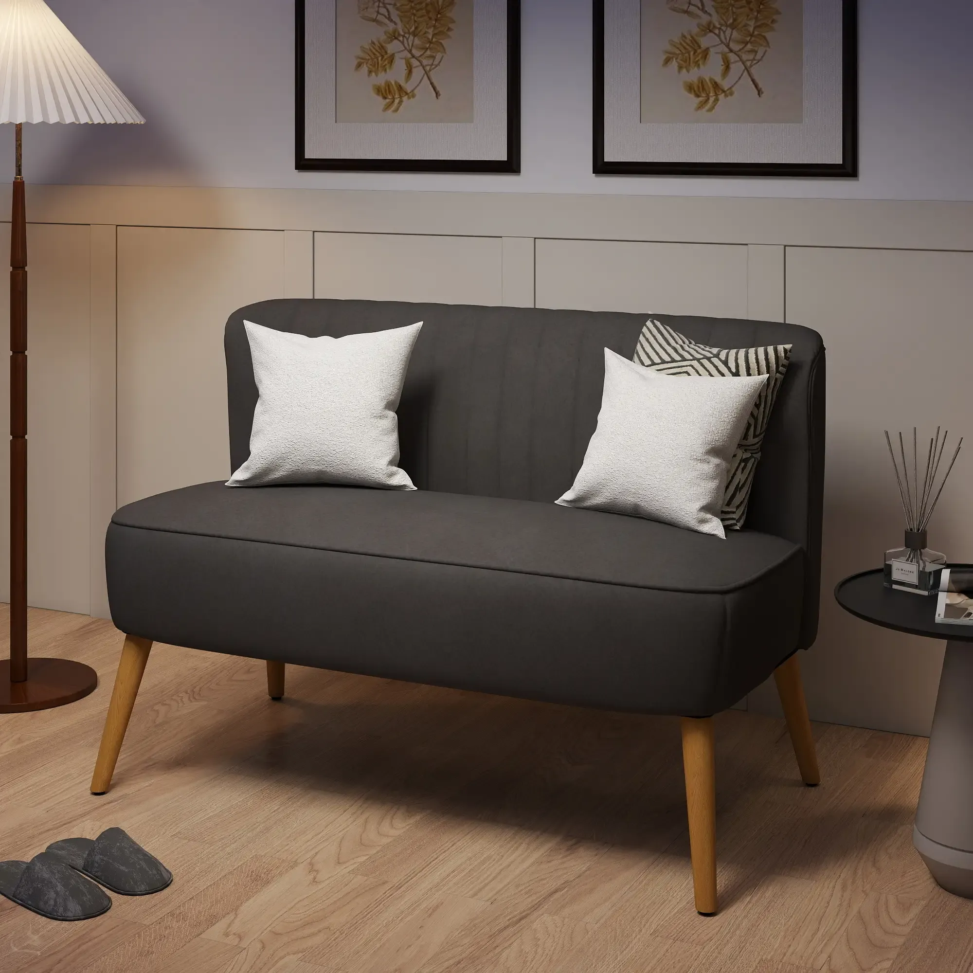 Eine graue Couch hat weiße Kissen. Auf jeder Seite befinden sich eine Lampe und ein kleiner Tisch. Zwei gerahmte Bilder hängen oben.