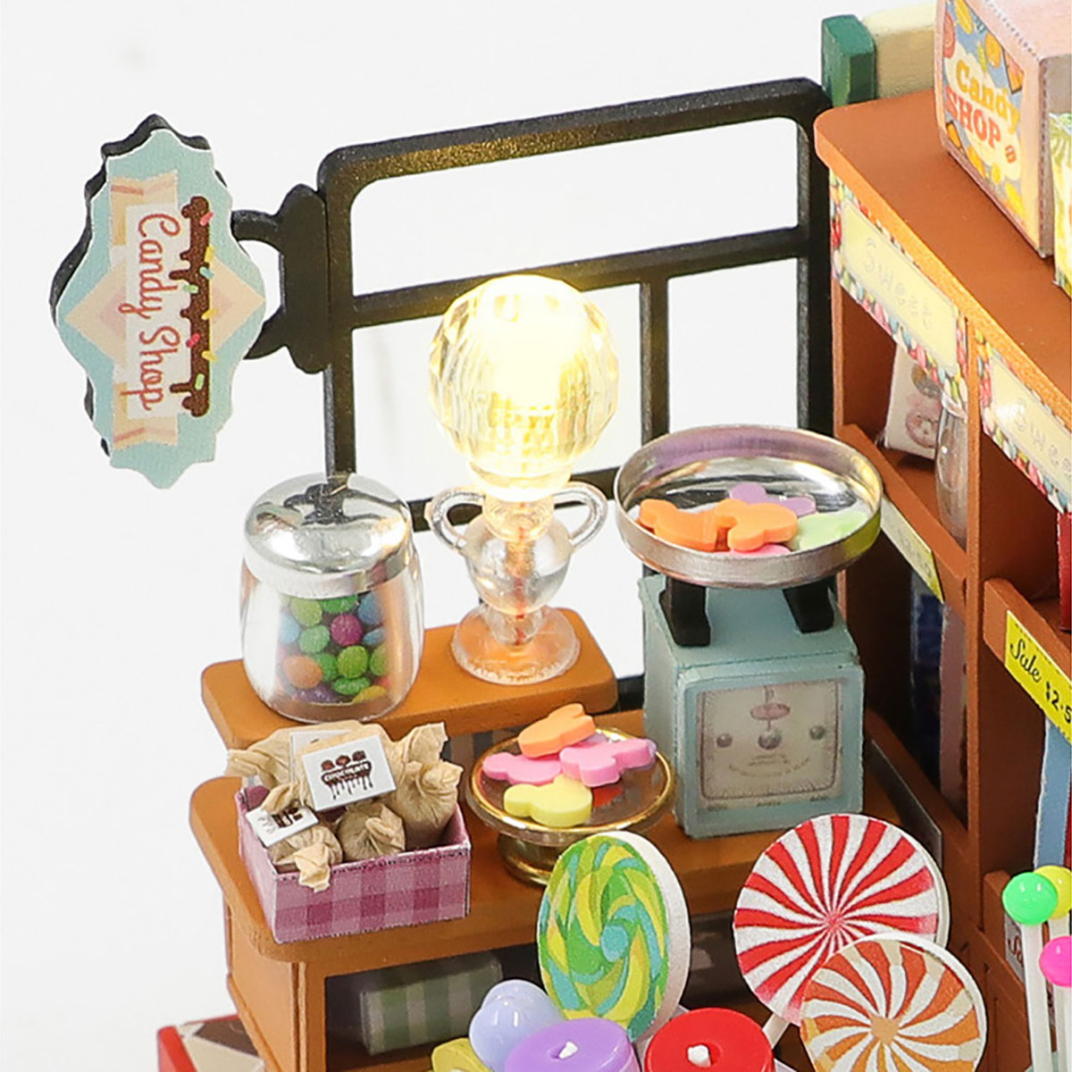 Miniatur-Süßwarenladen mit Schild. Enthält Lutscher, Gläser mit Süßigkeiten, eine Waage mit Süßigkeiten und ein Licht.