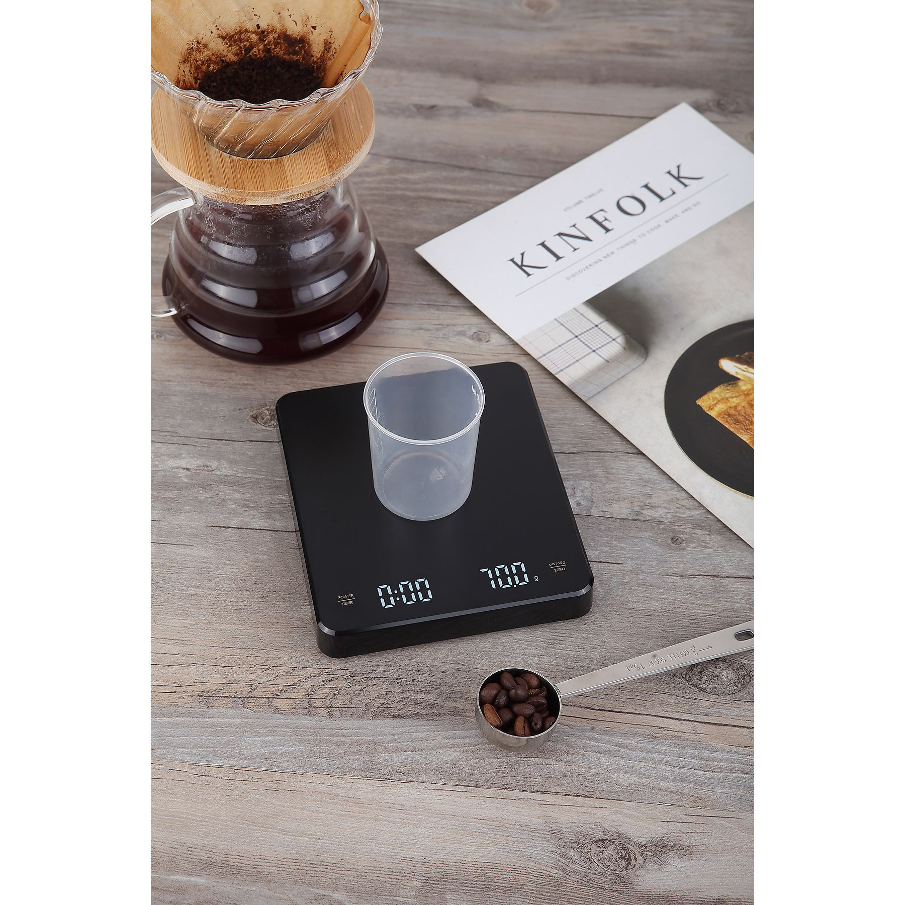 Kaffeezubereitung. Enthält eine Waage, Kaffeebohnen, eine Kaffeemaschine, ein Magazin und einen Messlöffel. Alles auf Holzoberfläche.