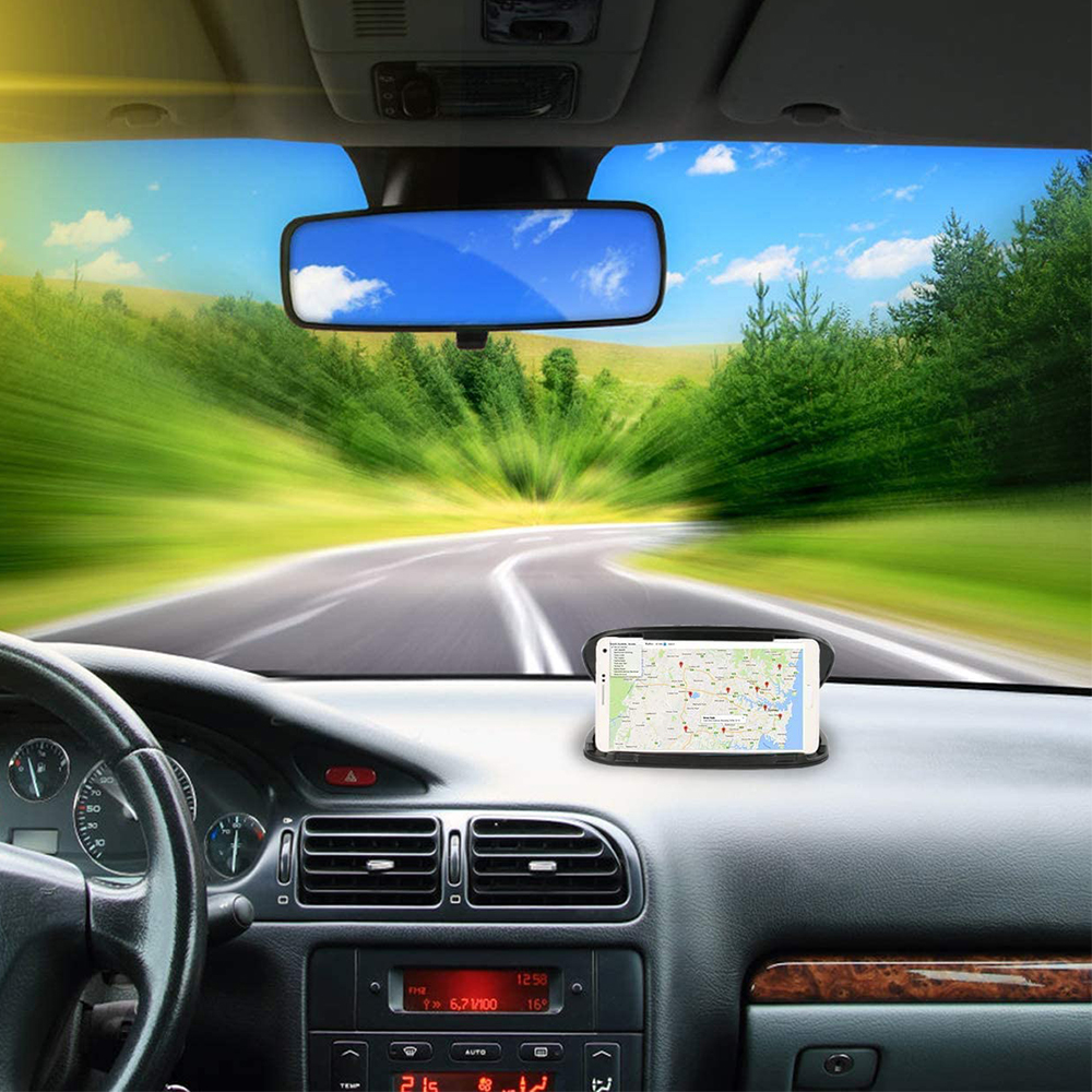 Ansicht von innen in einem Auto, das auf einer Straße fährt. Ein Telefon mit Karte befindet sich auf dem Armaturenbrett. Der Rückspiegel zeigt den Himmel.