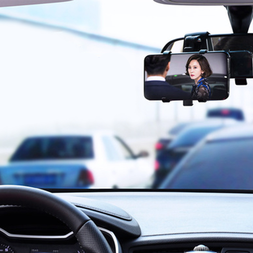 Ein Telefon zeigt eine Frau im Rückspiegel. Das Innere des Autos ist sichtbar, andere Autos im Hintergrund verschwommen.