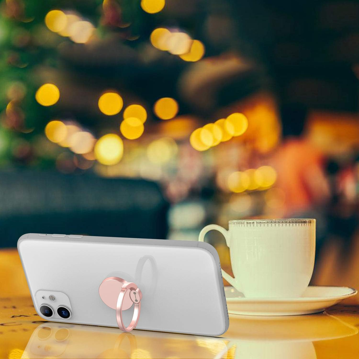 Ein Telefon mit Ringhalter liegt neben einer Teetasse auf einem Tisch. Bokeh-Lichter im Hintergrund erzeugen eine warme Atmosphäre.