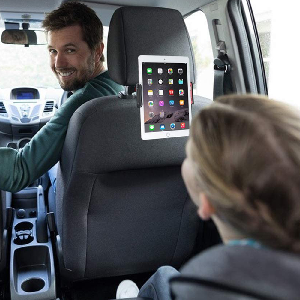 Ein Mann lächelt im Auto und schaut in die Kamera. Ein iPad ist an der Kopfstütze befestigt. Ein Kind sitzt hinten.