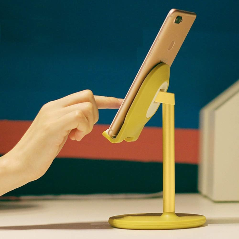 Eine Hand berührt ein Telefon auf einem gelben Ständer. Das Telefon ist goldfarben. Der Hintergrund ist blau, rot und weiß.