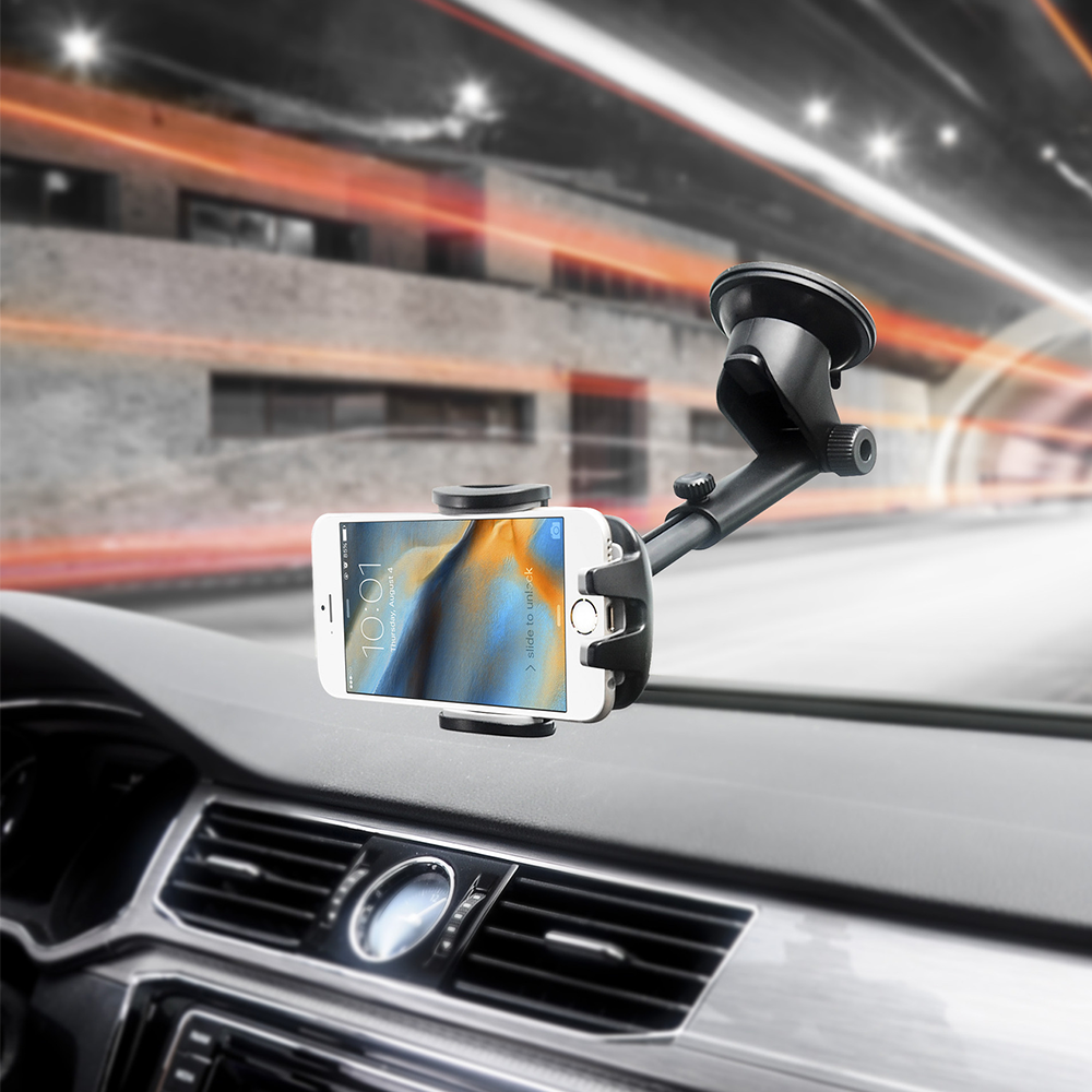 Ein weißes Smartphone ist an einer Halterung im Armaturenbrett befestigt. Der Bildschirm zeigt die Uhrzeit. Der Hintergrund zeigt einen verschwommenen Tunnel.