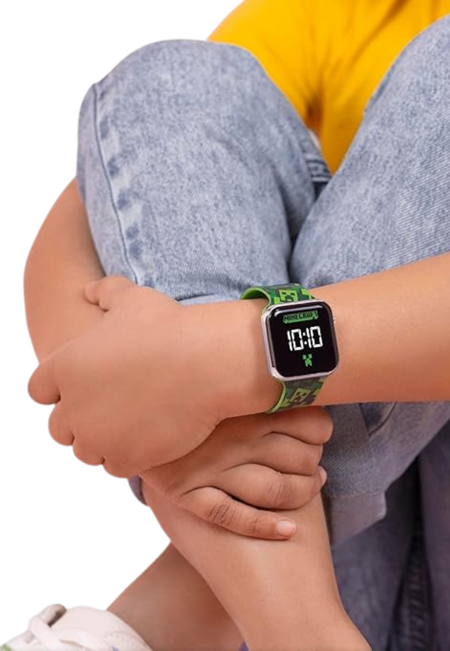 Ein Kind mit einer Minecraft-Uhr, die 10:10 anzeigt. Das Kind trägt ein gelbes Hemd und blaue Jeans.