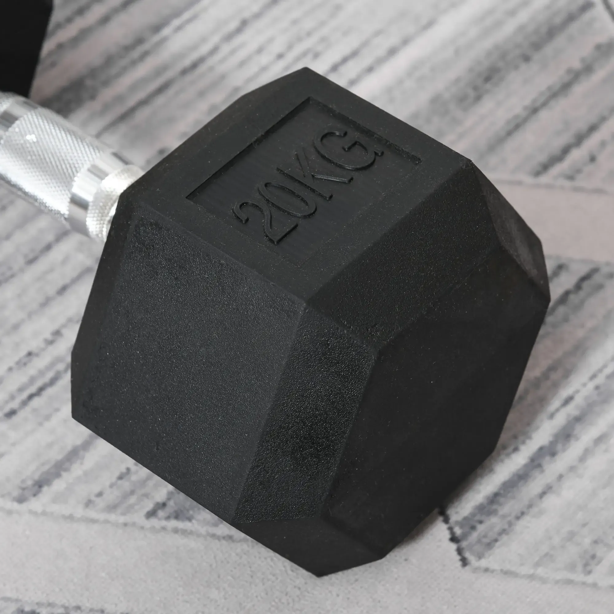 Eine 20 kg schwere, schwarze Hantel. Der Griff ist silberfarben. Sie liegt auf einer grau-weiß gemusterten Oberfläche.