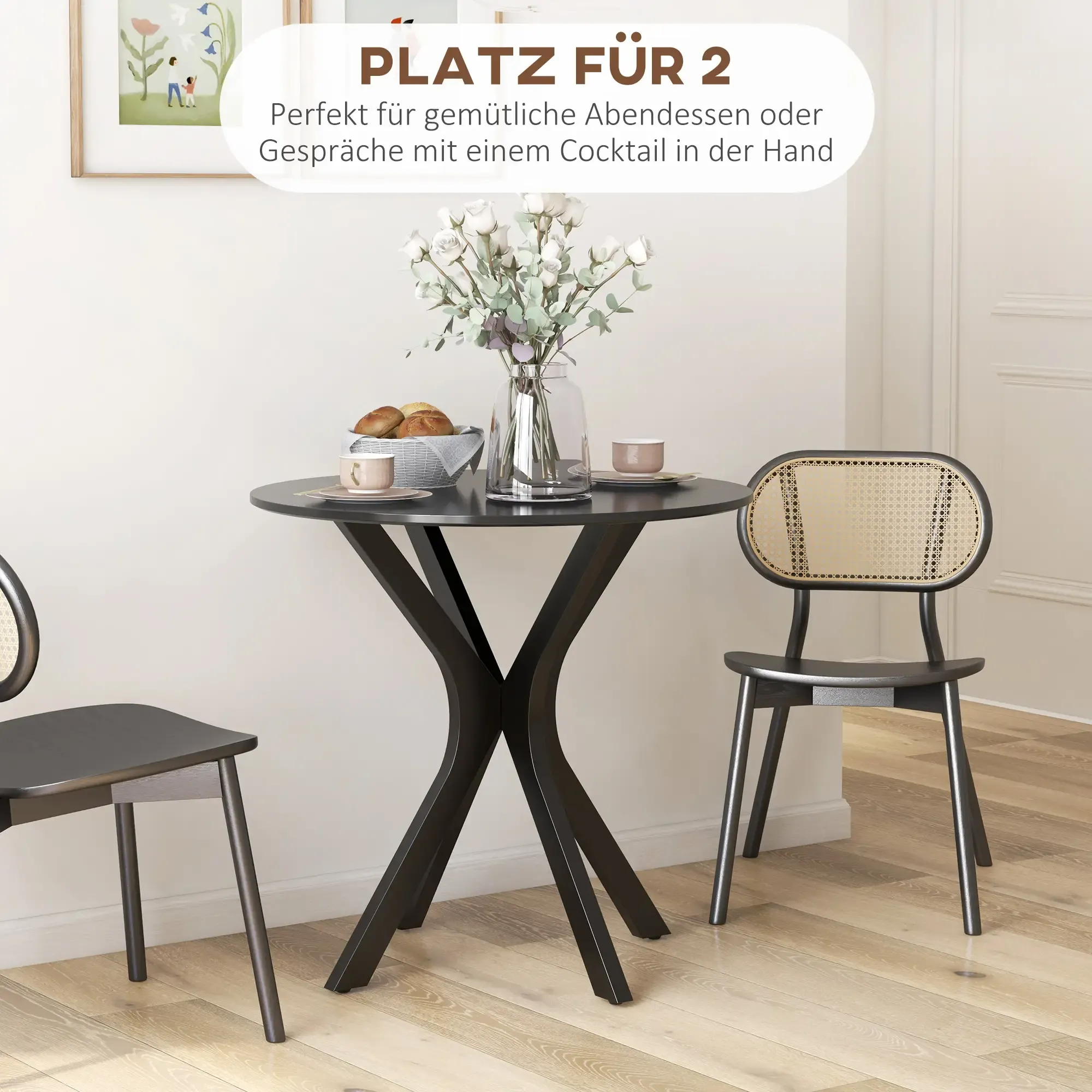 Ein kleiner runder Tisch mit zwei Stühlen. Eine Vase mit Blumen auf dem Tisch. Zwei Tassen, ein Brotkorb und ein Gemälde.