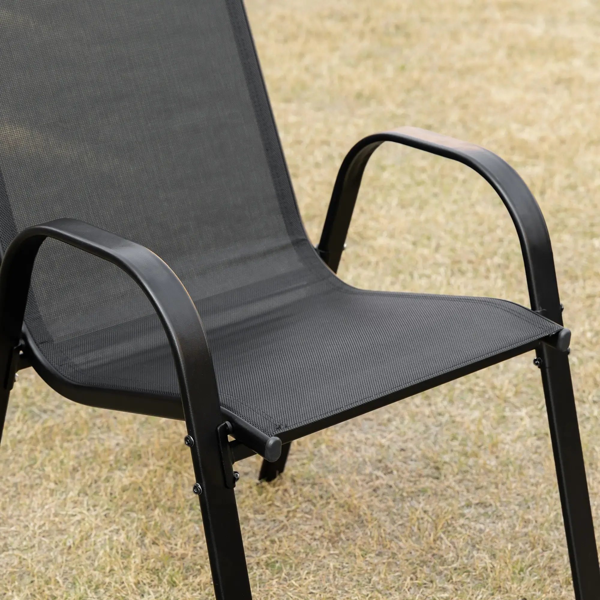 Ein schwarzer Metall-Gartenstuhl. Der Stuhl hat eine Netz-Sitzfläche und -Rückenlehne sowie gebogene Armlehnen.