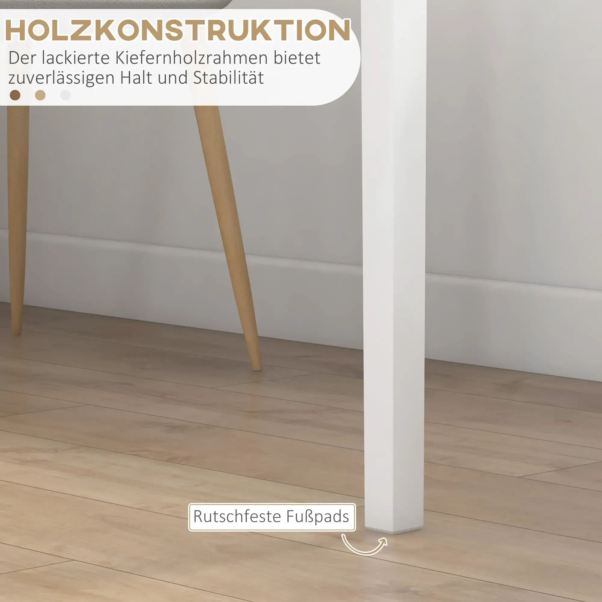 Holztischbeine auf Holzboden, mit weißem Tischbein im Vordergrund. Im Hintergrund eine weiße Wand.
