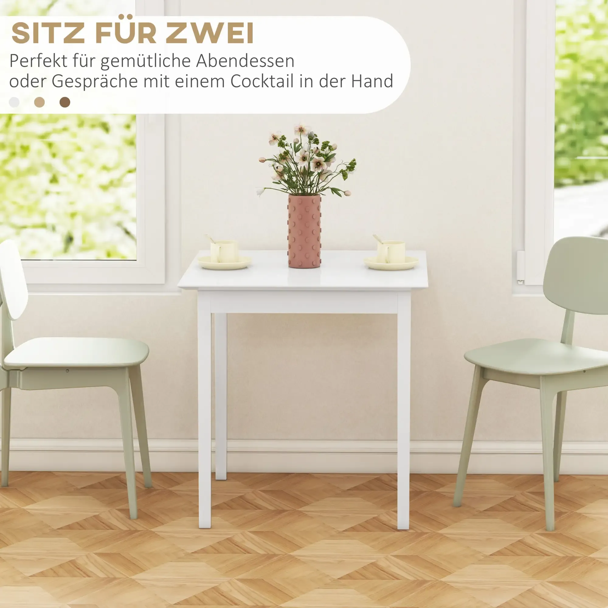 Kleiner weißer Tisch mit zwei Stühlen. Eine Blumenvase steht auf dem Tisch. Fenster und Holzboden sind sichtbar.