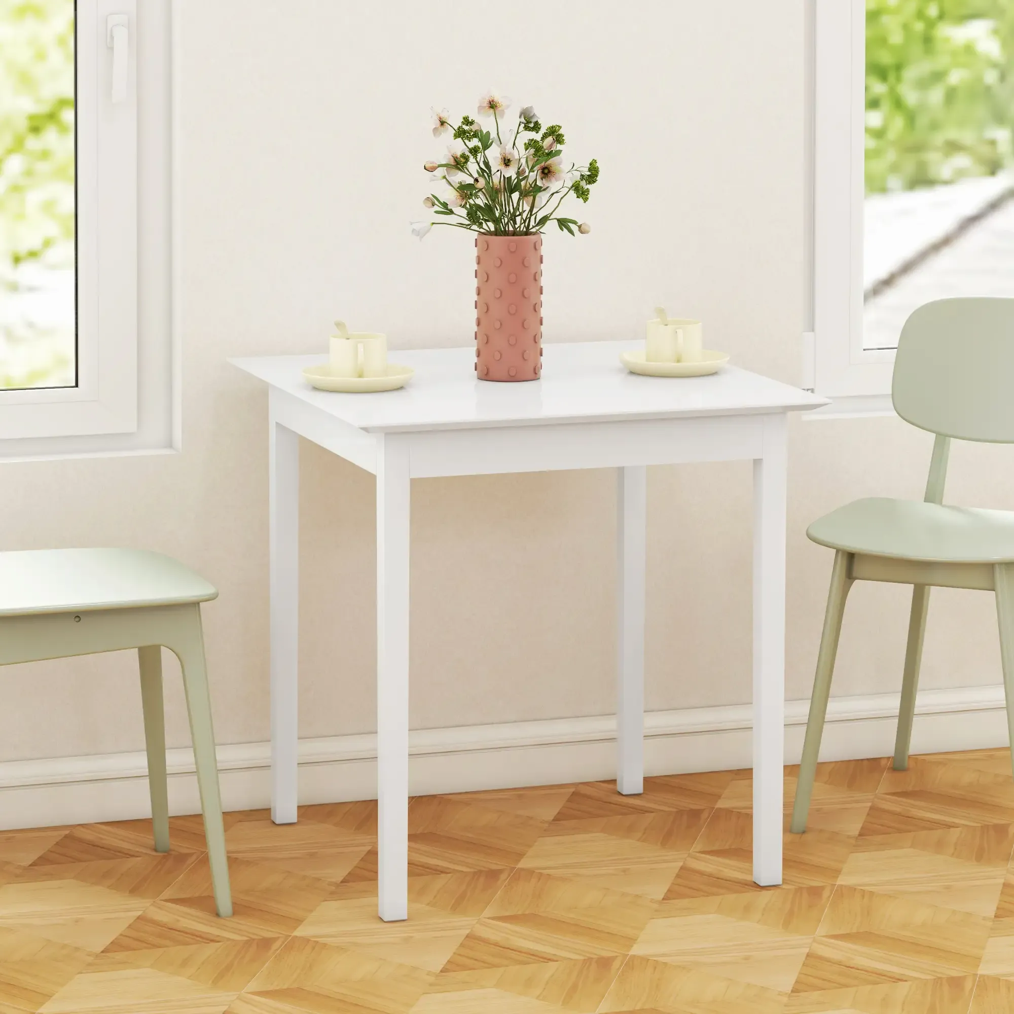 Ein weißer Tisch mit Blumen in einer Vase, zwei Stühlen und zwei Tassen. Der Boden ist aus Holz. Fenster sind im Hintergrund.