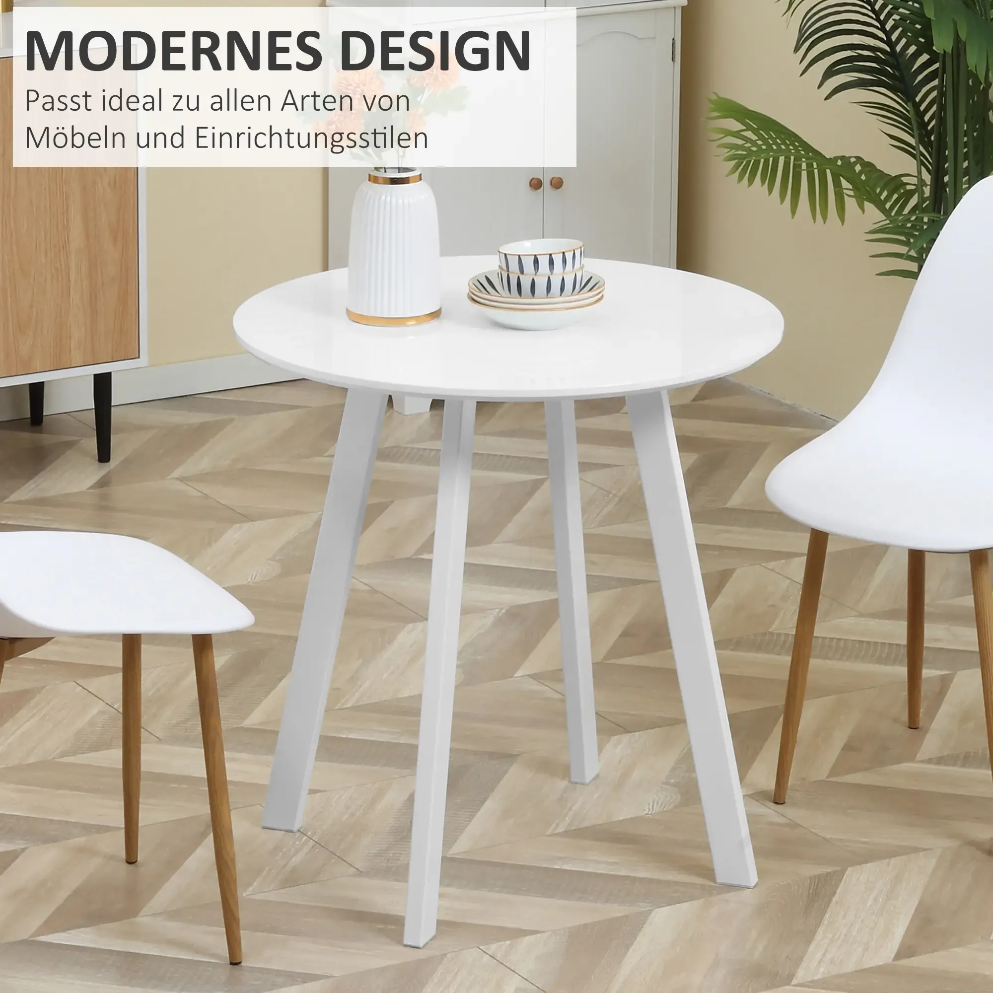 Ein weißer runder Tisch mit einer Vase und Geschirr darauf. Zwei weiße Stühle stehen daneben. Holzfußboden und Hintergrund.