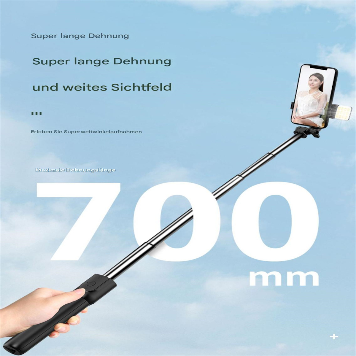 Eine Hand hält einen schwarzen Selfie-Stick mit einem Telefon, das eine Frau zeigt. Es steht '700 mm' und hat deutschen Text.