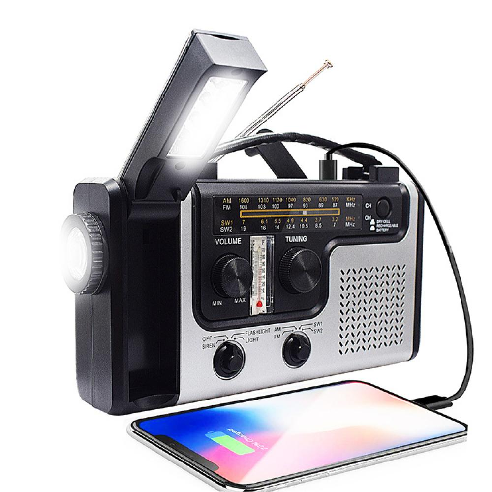 Ein schwarz-silbernes Notfallradio mit Taschenlampe und Telefonladung. Das Telefon ist unten und das Licht ist an.