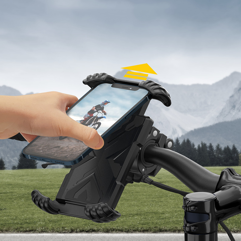 Eine Hand, die ein Telefon in einer schwarzen Telefonhalterung an einem Fahrrad hält. Das Telefon zeigt einen Motocross-Fahrer. Berge im Hintergrund.