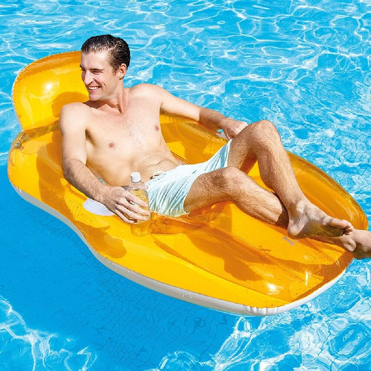 Ein Mann entspannt sich auf einem gelben aufblasbaren Floß in einem blauen Pool. Er hält eine Wasserflasche und trägt hellblaue Shorts.