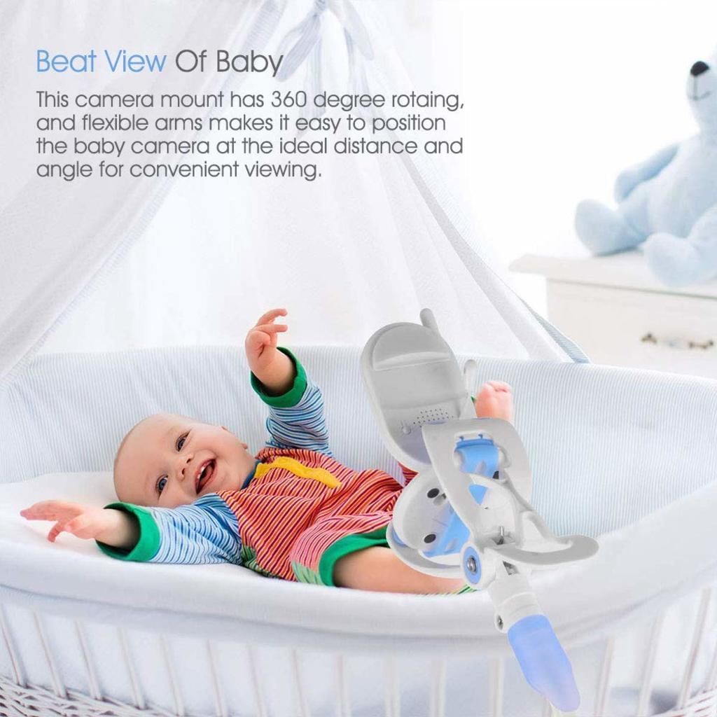 Ein Baby lächelt in einem Kinderbett mit einer Kamerahalterung. Die Halterung ist weiß und blau. Das Baby trägt ein gestreiftes Hemd.