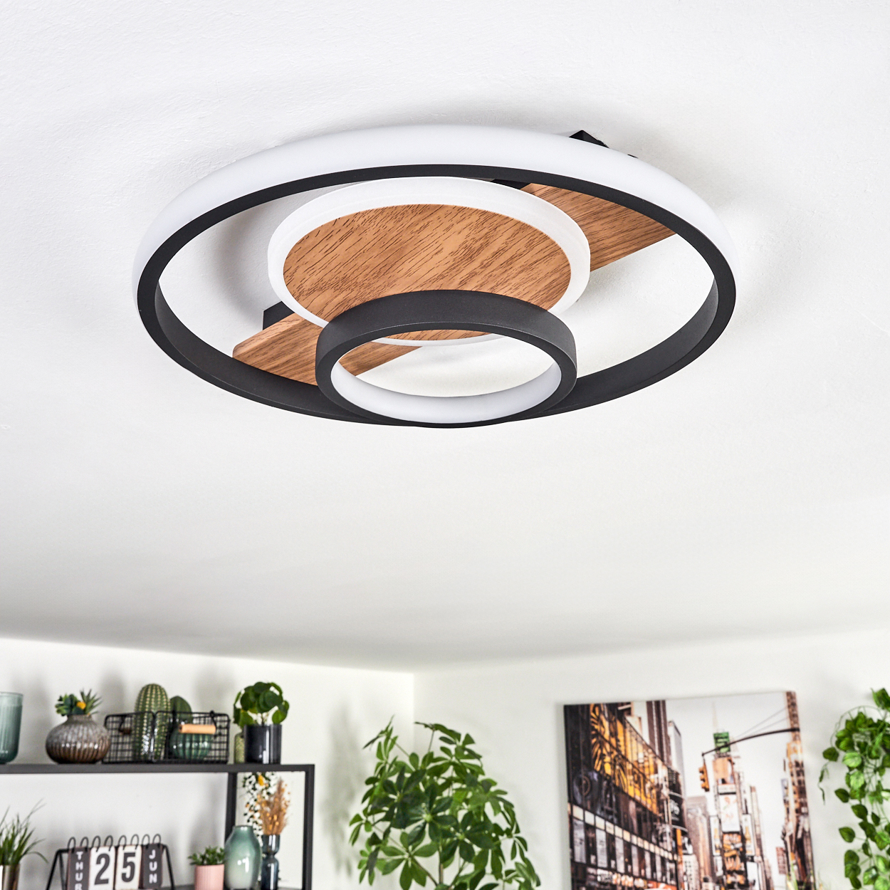 Eine moderne Deckenleuchte mit kreisförmigem Design. Es hat eine Holzmitte, schwarze und weiße Ringe. Der Hintergrund zeigt Wohnkultur.