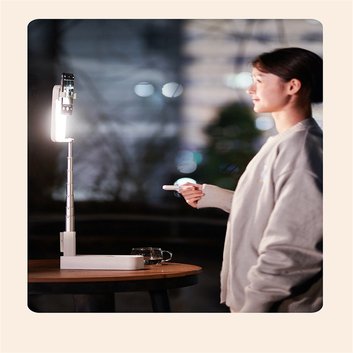 Frau mit Licht und Telefonhalter. Ein Tisch mit einer Tasse und einem Licht. Nachtszene mit Bokeh-Hintergrund.