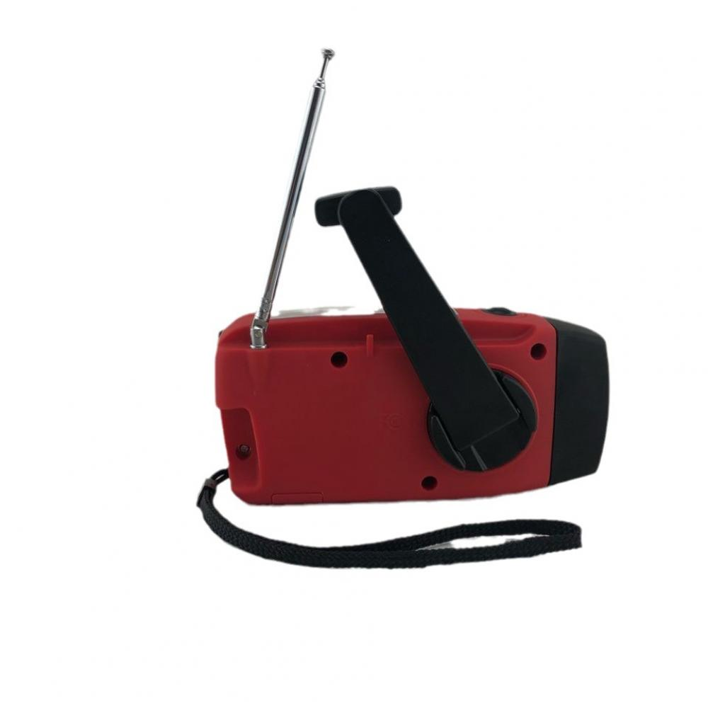 Ein rotes Handkurbelradio mit schwarzem Griff und Antenne. Unten ist ein schwarzer Riemen. Der Hintergrund ist weiß.