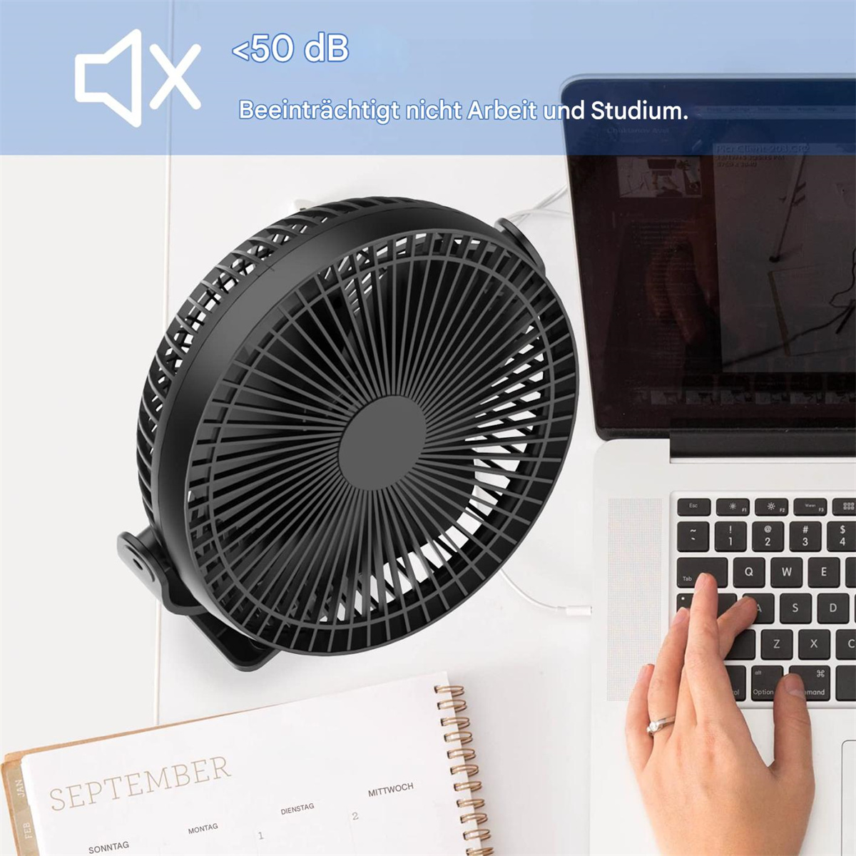 Ein schwarzer Ventilator neben einem Laptop, eine Hand tippt, und ein Kalender liegt auf dem Tisch. Der Ventilator ist leise.