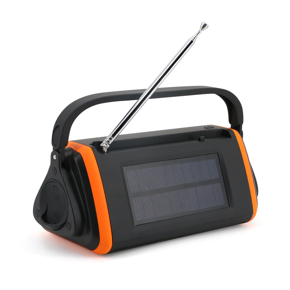 Ein schwarz-oranges Radio mit Solarpanel und Antenne. Es hat einen Griff oben und steht auf einer weißen Oberfläche.