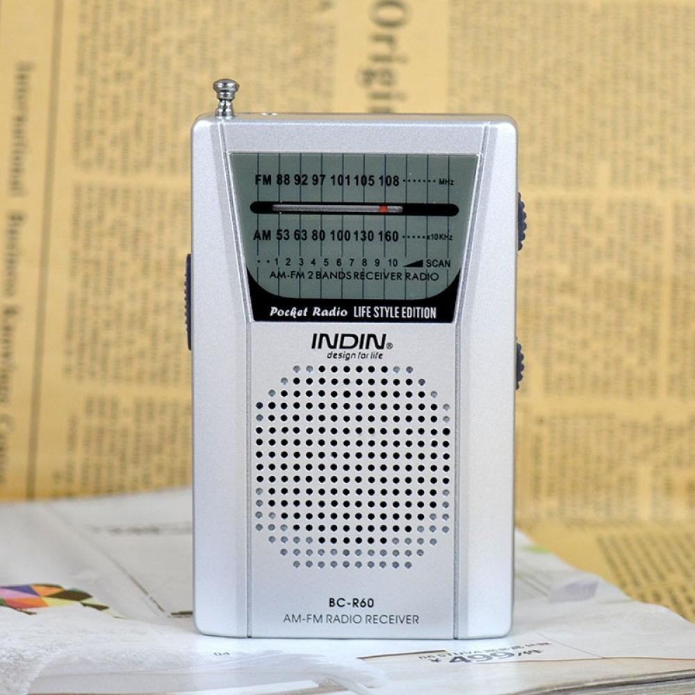 Ein silbernes Taschenradio liegt auf einer Zeitung. Es hat einen Lautsprecher, einen Drehknebel und ein Frequenzdisplay. Das Radio ist mit INDIN beschriftet.