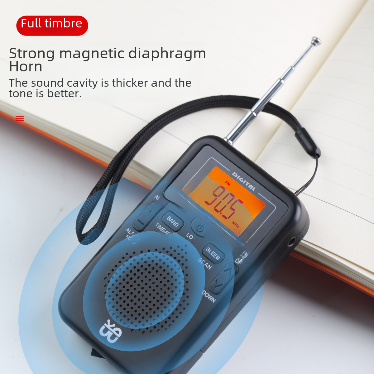 Ein schwarzes tragbares Radio mit Antenne liegt auf einem Notizbuch. Das Display zeigt 90,5 MHz. Text enthält 'Full timbre' und 'Strong magnetic diaphragm'.