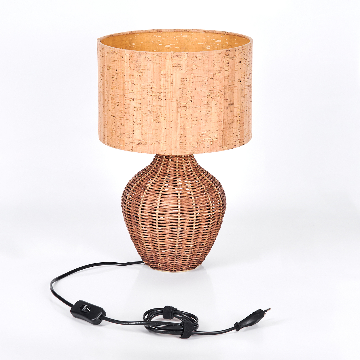 Eine Tischlampe mit gewebtem Sockel und einem Korkschirm. Die Lampe hat ein schwarzes Netzkabel und einen Schalter.
