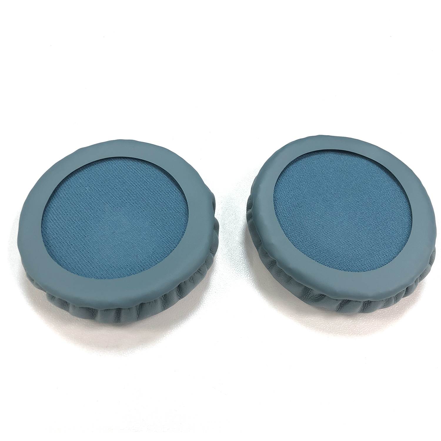 Dwie niebieskie nauszniki na białym tle. Każda nausznica ma niebieski środek z tkaniny i szary gumowy pierścień.