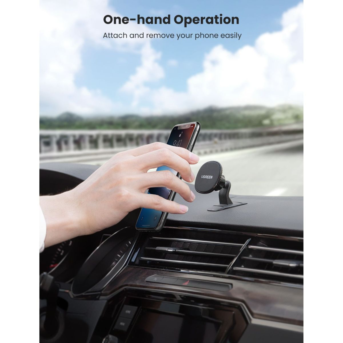 Ręka umieszcza telefon na uchwycie samochodowym. Telefon pokazuje godzinę 9:41. W tle pasmo górskie.