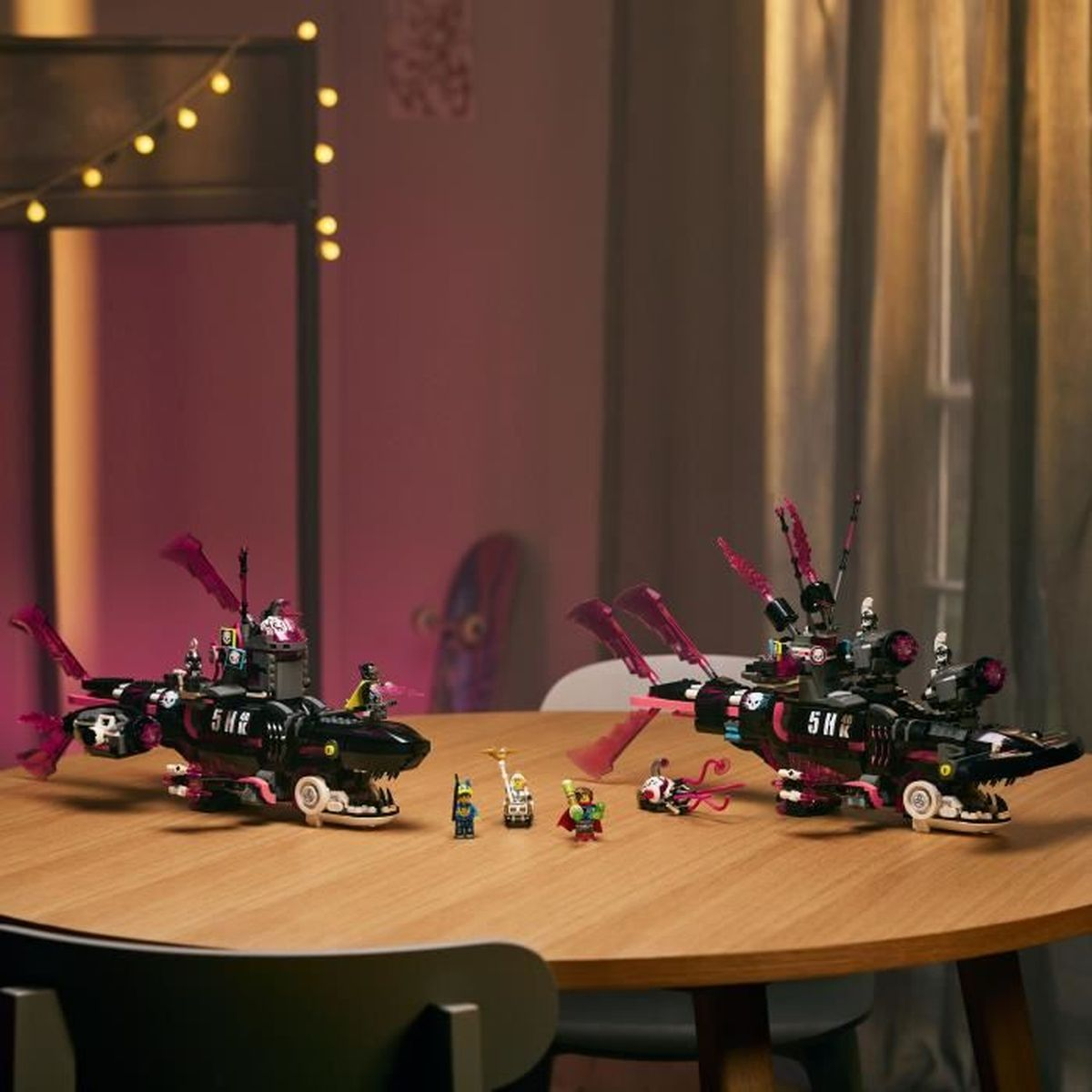 Dwa czarne zestawy Lego w kształcie rekina stoją na drewnianym stole z minifigurkami. Tło ma różowy odcień i dekoracyjne oświetlenie.