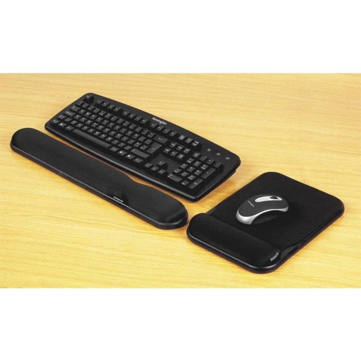 Teclado negro, reposamuñecas, ratón y alfombrilla sobre una superficie de madera. El ratón es plateado y negro.