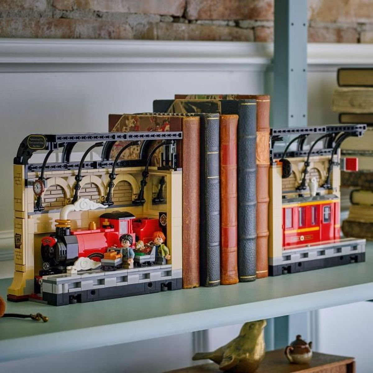 Un modelo Lego del Expreso de Hogwarts con libros. El tren es rojo, con personajes. Los libros son marrones, negros y rojos.