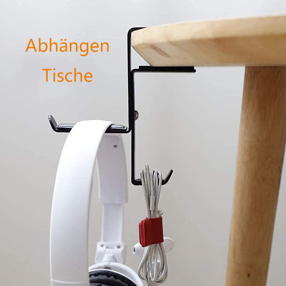 Ein schwarzer Kopfhörerhalter an einem Holztisch. Weiße Kopfhörer hängen daran, und ein Bündel weißer Kabel wird von einem roten Riemen gehalten.