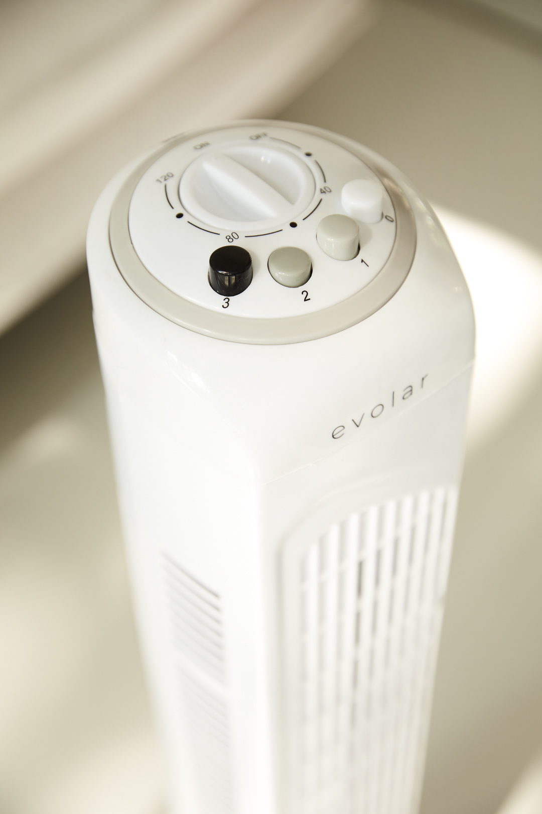 A white Evolar fan with a control panel featuring a dial and buttons. The fan is on a light-colored surface.