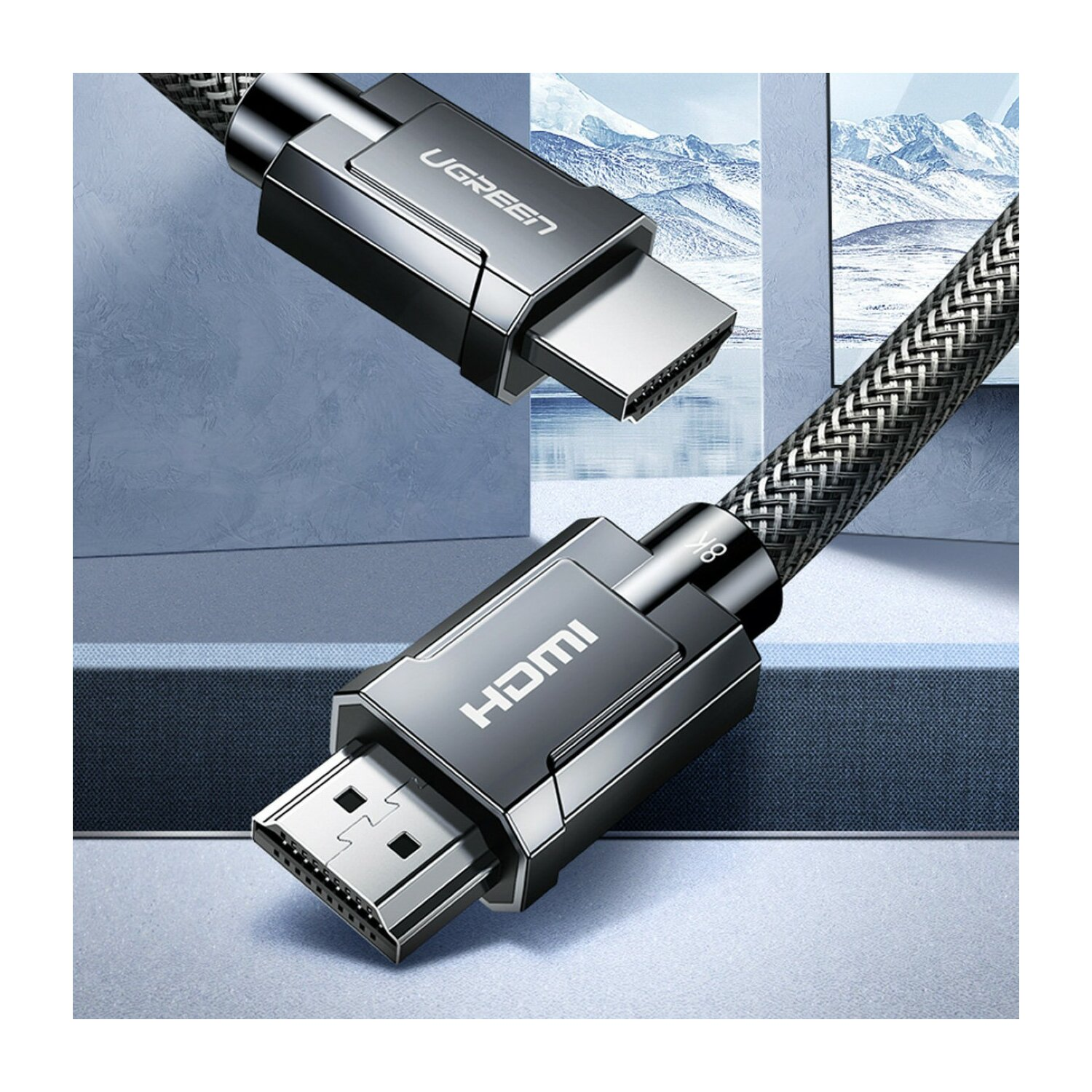 Widoczne są dwa kable HDMI, jeden z logo UGREEN, a drugi z HDMI. Kable mają pleciony wzór. Tło jest niebieskie.