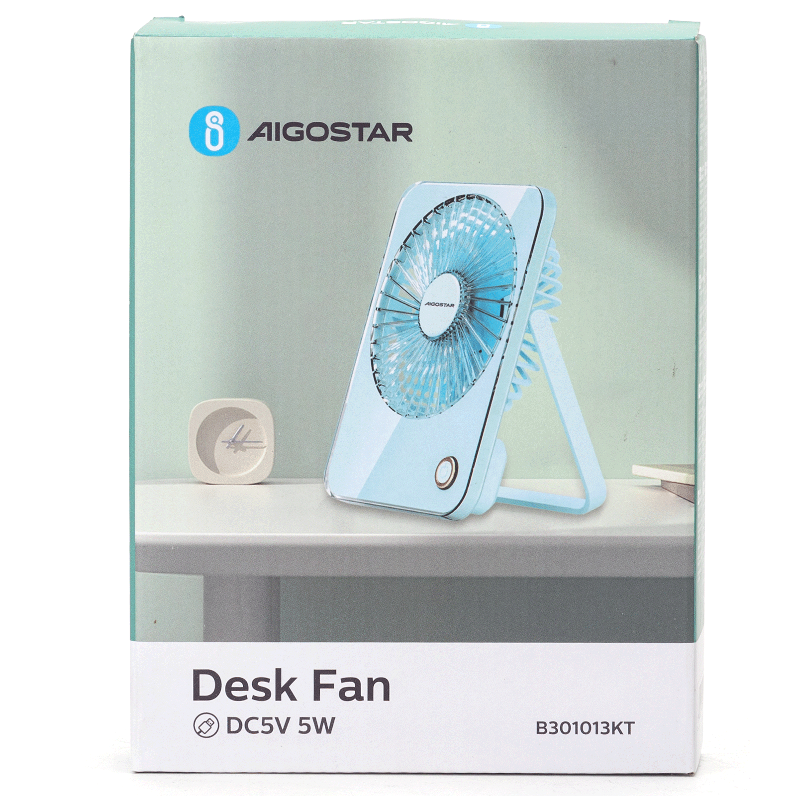 Caja de un ventilador de escritorio. El ventilador es azul claro. Está sobre una mesa blanca. La caja tiene el nombre Aigostar y Desk Fan.